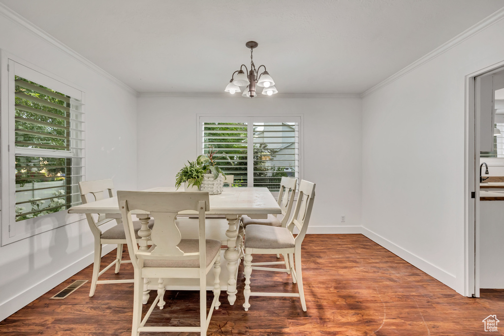 Dining space featuring a chandelier, ornamental molding, wood finished floors, and baseboards