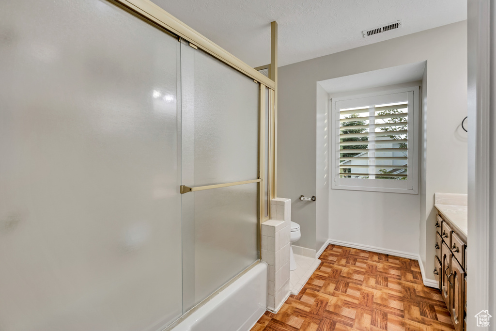 Full bathroom featuring vanity, toilet, bath / shower combo with glass door, and baseboards