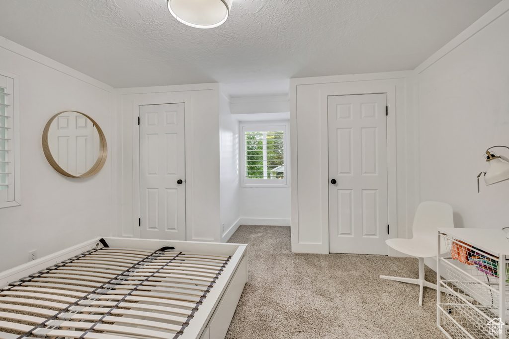 Foyer featuring a textured ceiling, carpet flooring, and baseboards