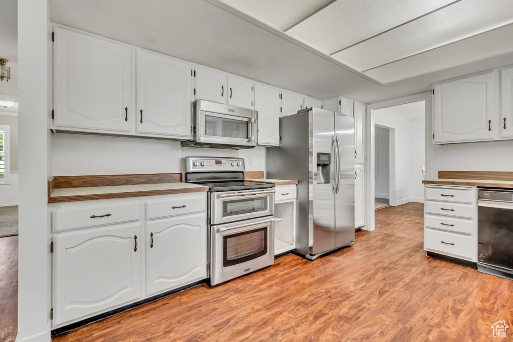 Kitchen featuring appliances with stainless steel finishes, white cabinetry, and light wood finished floors