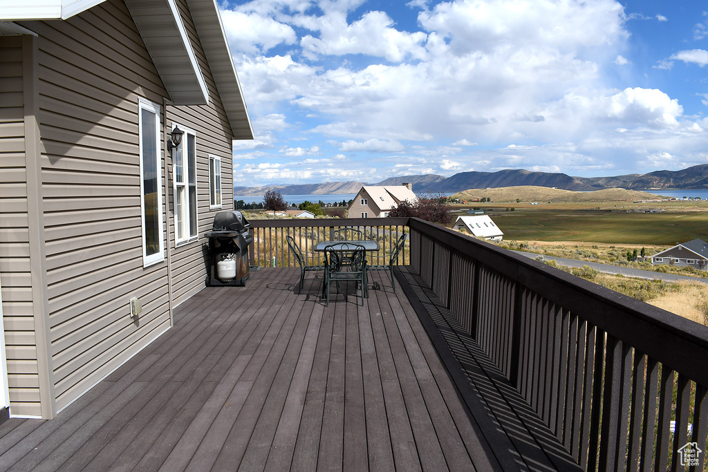 Wooden deck with a mountain view, outdoor dining space, and a grill
