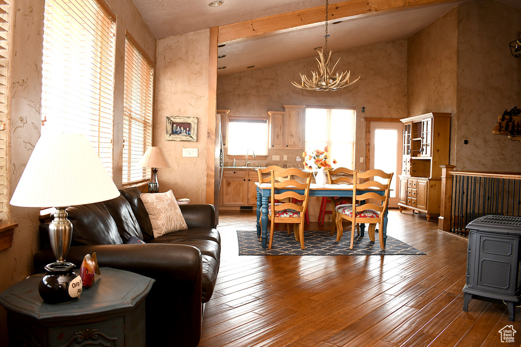 Living room featuring a chandelier, vaulted ceiling, hardwood / wood-style flooring, and a wood stove