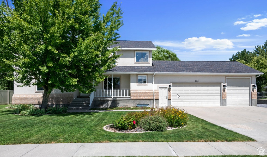 View of front of property featuring brick siding, an attached garage, a porch, driveway, and stucco siding