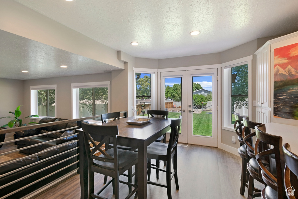 Dining space with recessed lighting, french doors, wood finished floors, a textured ceiling, and baseboards