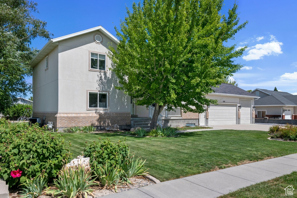 View of front of home featuring brick siding, a front lawn, driveway, a garage, and stucco siding