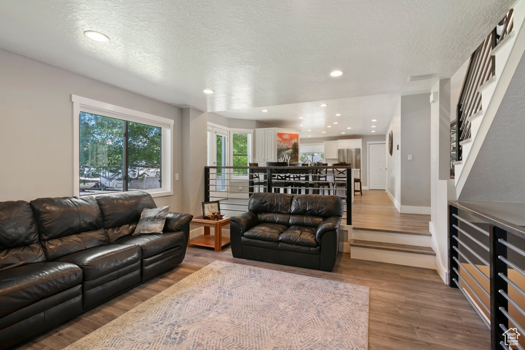Living area with wood finished floors, a textured ceiling, recessed lighting, and baseboards