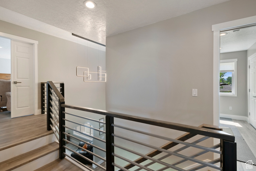 Stairway featuring wood finished floors, baseboards, a textured ceiling, and recessed lighting