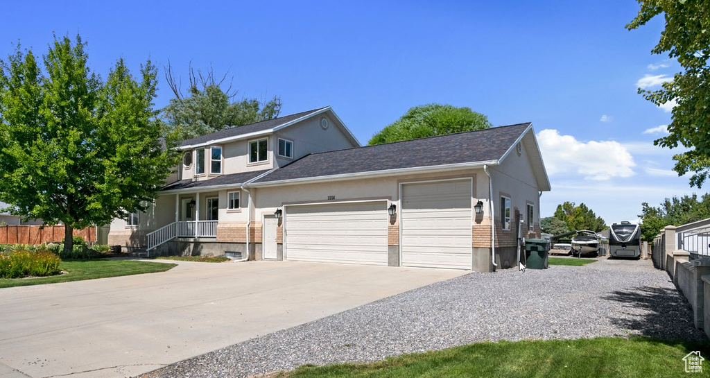 View of front of property featuring an attached garage, concrete driveway, brick siding, stucco siding, and a shingled roof