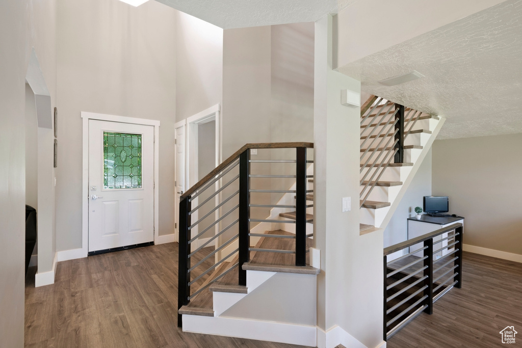 Entryway with wood finished floors, baseboards, stairway, and a high ceiling