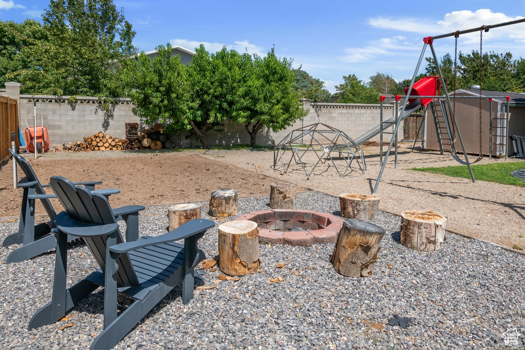Fenced backyard featuring a fire pit and a playground