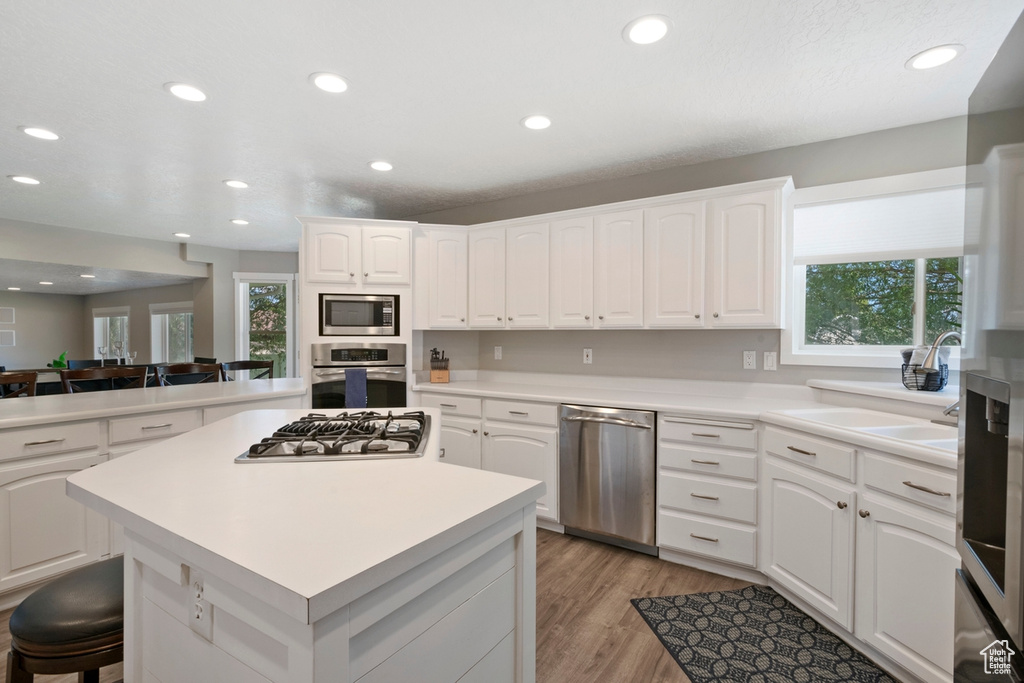 Kitchen featuring stainless steel appliances, recessed lighting, a center island, light wood-style floors, and light countertops