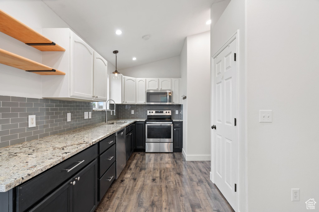 Kitchen with appliances with stainless steel finishes, open shelves, white cabinetry, decorative backsplash, and dark wood finished floors
