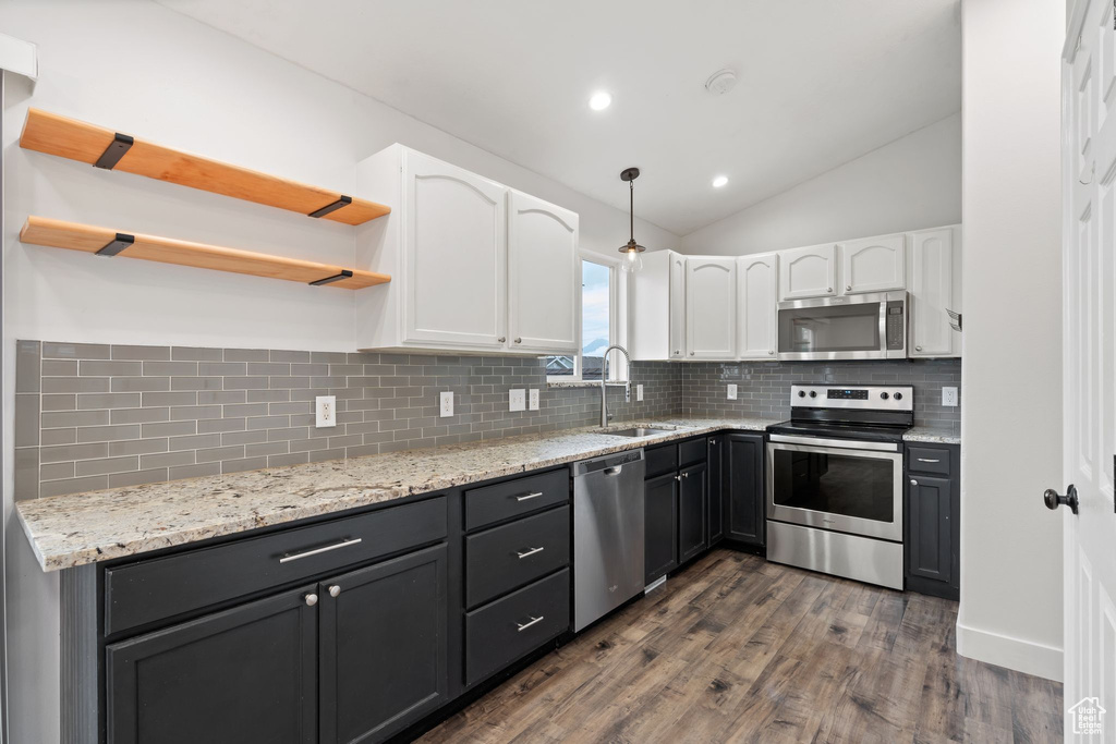 Kitchen with appliances with stainless steel finishes, open shelves, white cabinetry, a sink, and lofted ceiling