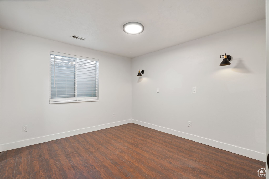 Empty room featuring baseboards and dark wood-style floors