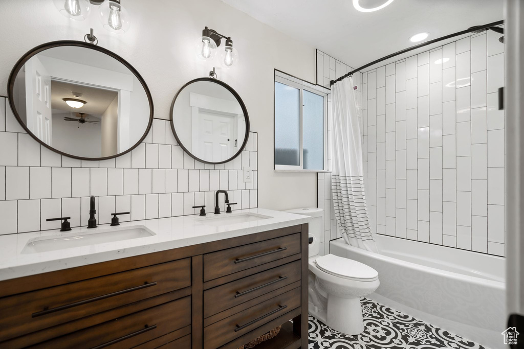 Bathroom with double vanity, shower / bath combination with curtain, toilet, tile patterned flooring, and tasteful backsplash