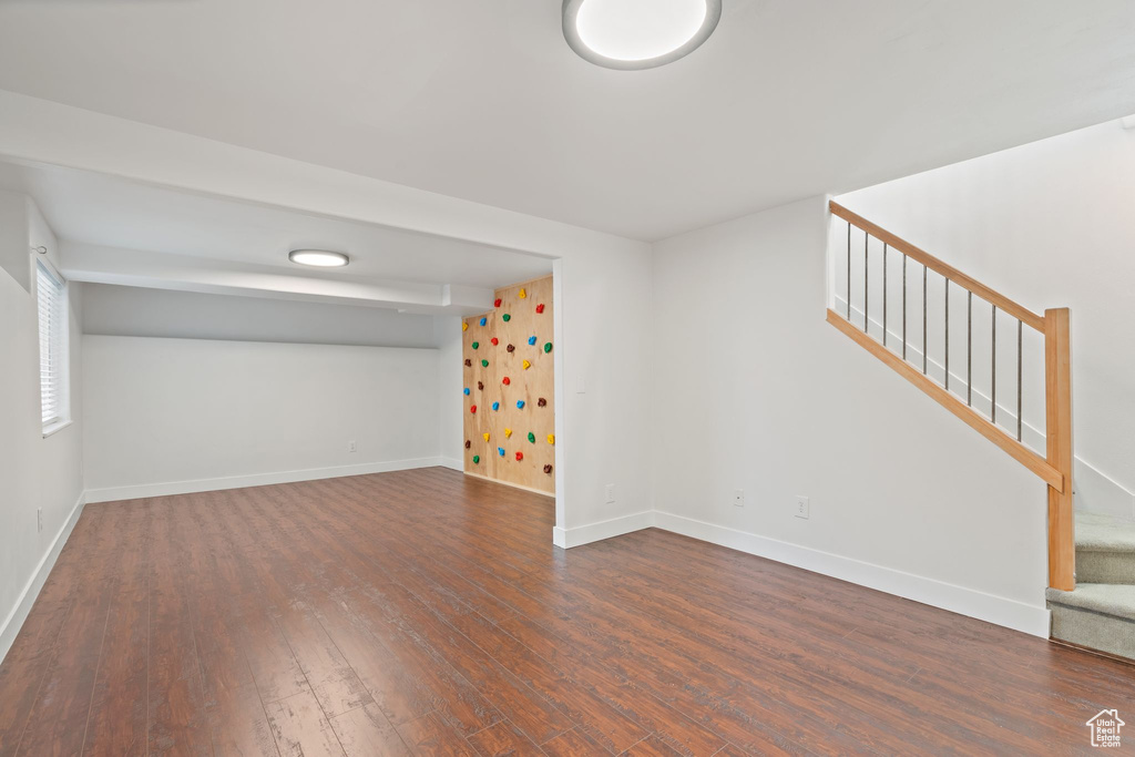 Spare room featuring dark wood-style floors, stairway, and baseboards