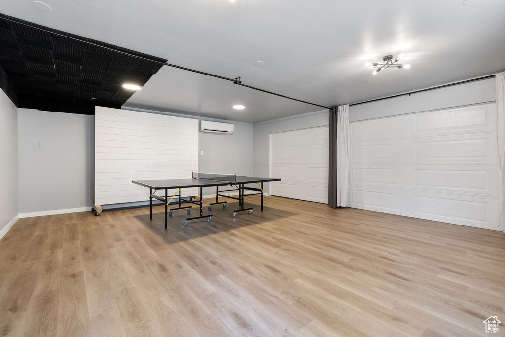 Rec room with a wall mounted air conditioner, light wood-type flooring, baseboards, and recessed lighting