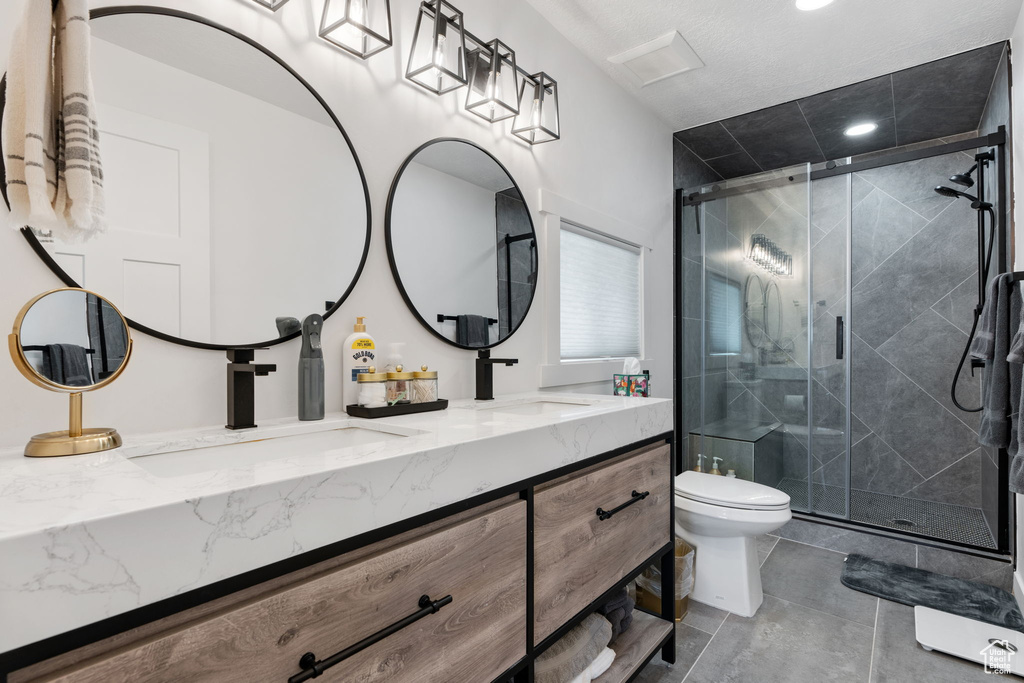 Bathroom with double vanity, toilet, a stall shower, and recessed lighting
