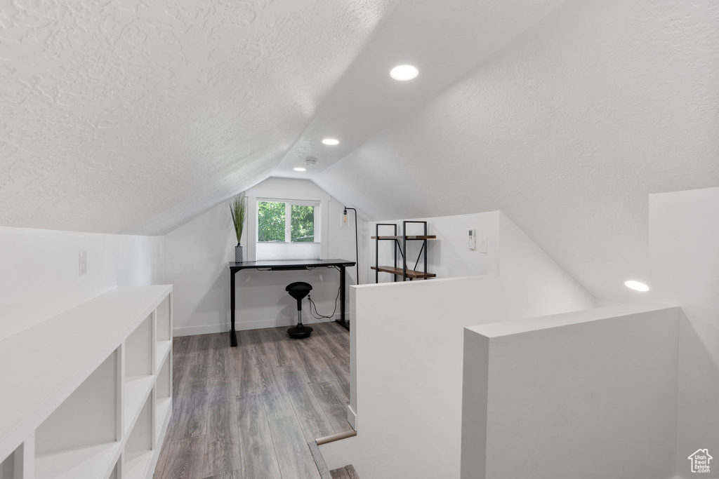 Additional living space featuring a textured ceiling, wood finished floors, lofted ceiling, recessed lighting, and baseboards