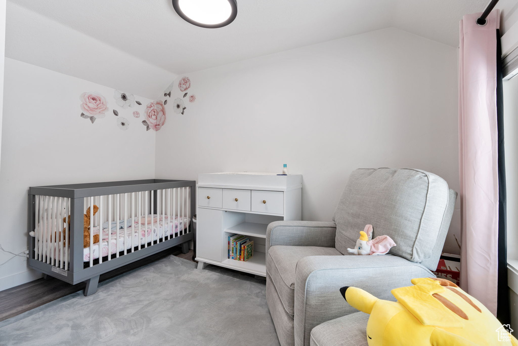 Bedroom with vaulted ceiling, carpet flooring, and a crib