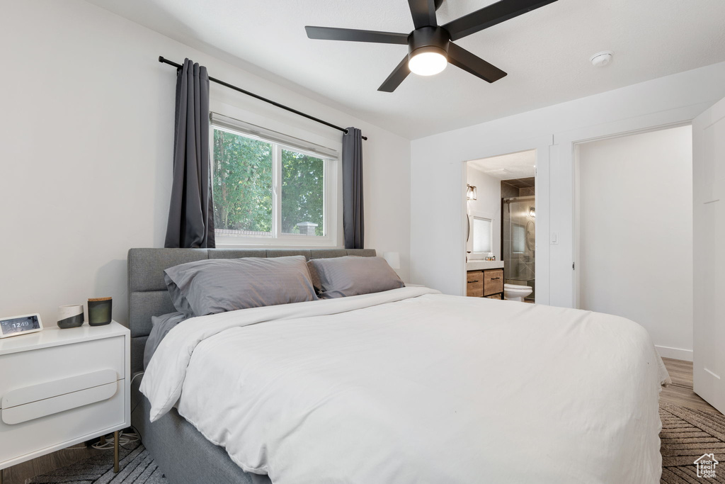 Bedroom with connected bathroom, wood finished floors, and a ceiling fan