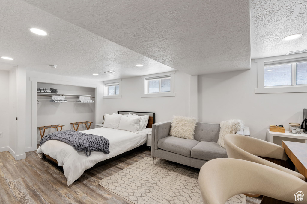 Bedroom featuring wood finished floors, a textured ceiling, recessed lighting, and baseboards