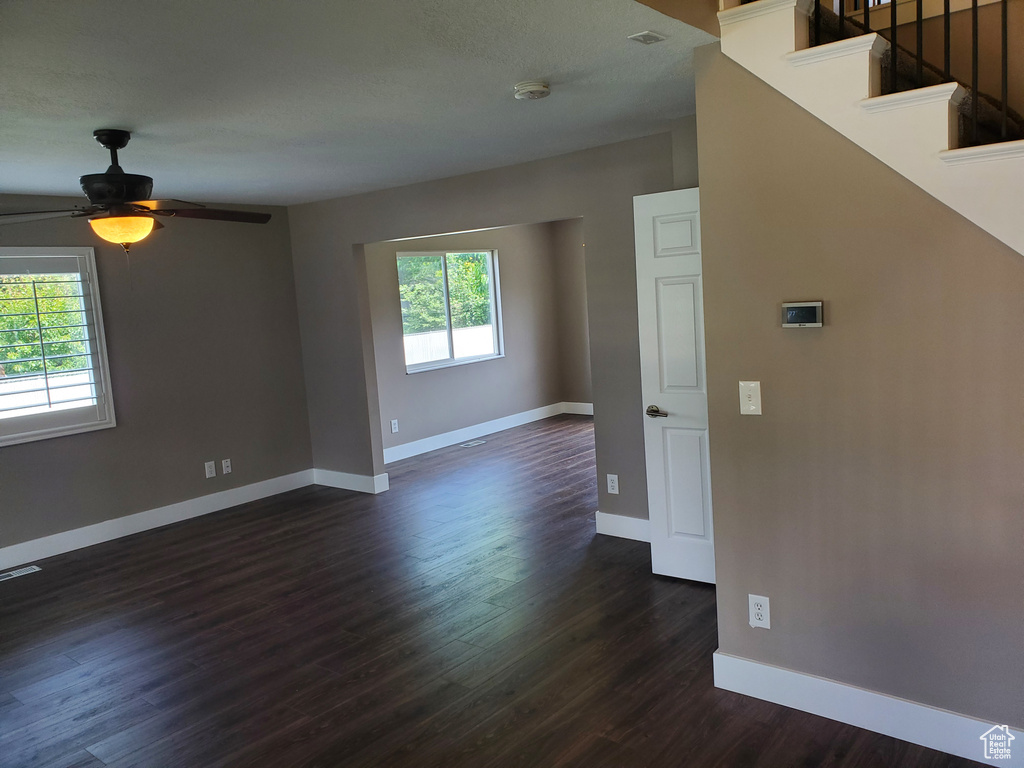 Spare room with dark wood-style flooring, a smoke detector, baseboards, ceiling fan, and stairs