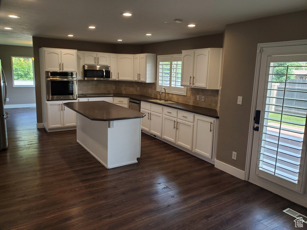 Kitchen featuring stainless steel appliances, dark countertops, recessed lighting, baseboards, and plenty of natural light