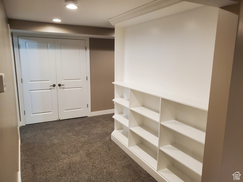 Hallway with dark carpet, recessed lighting, and baseboards