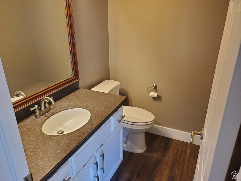 Bathroom with wood finished floors, vanity, toilet, and baseboards
