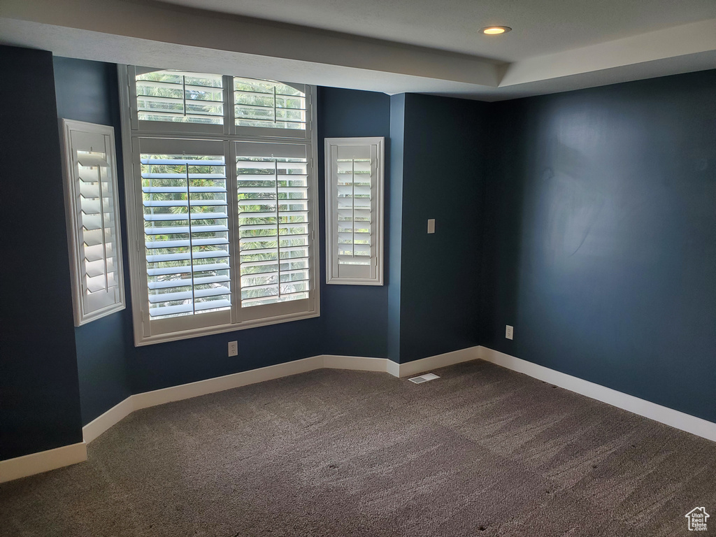 Empty room featuring dark colored carpet, baseboards, and recessed lighting