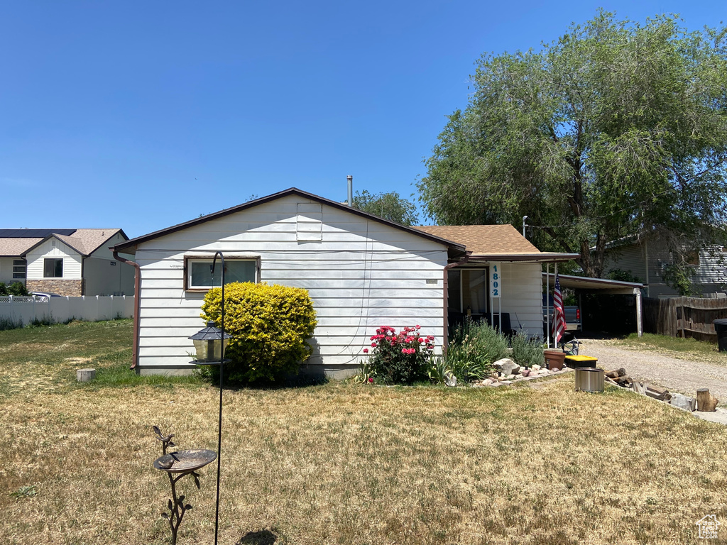 Rear view of property with an attached carport and gravel driveway