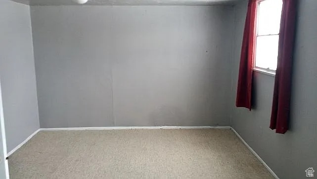 Spare room featuring carpet floors and baseboards