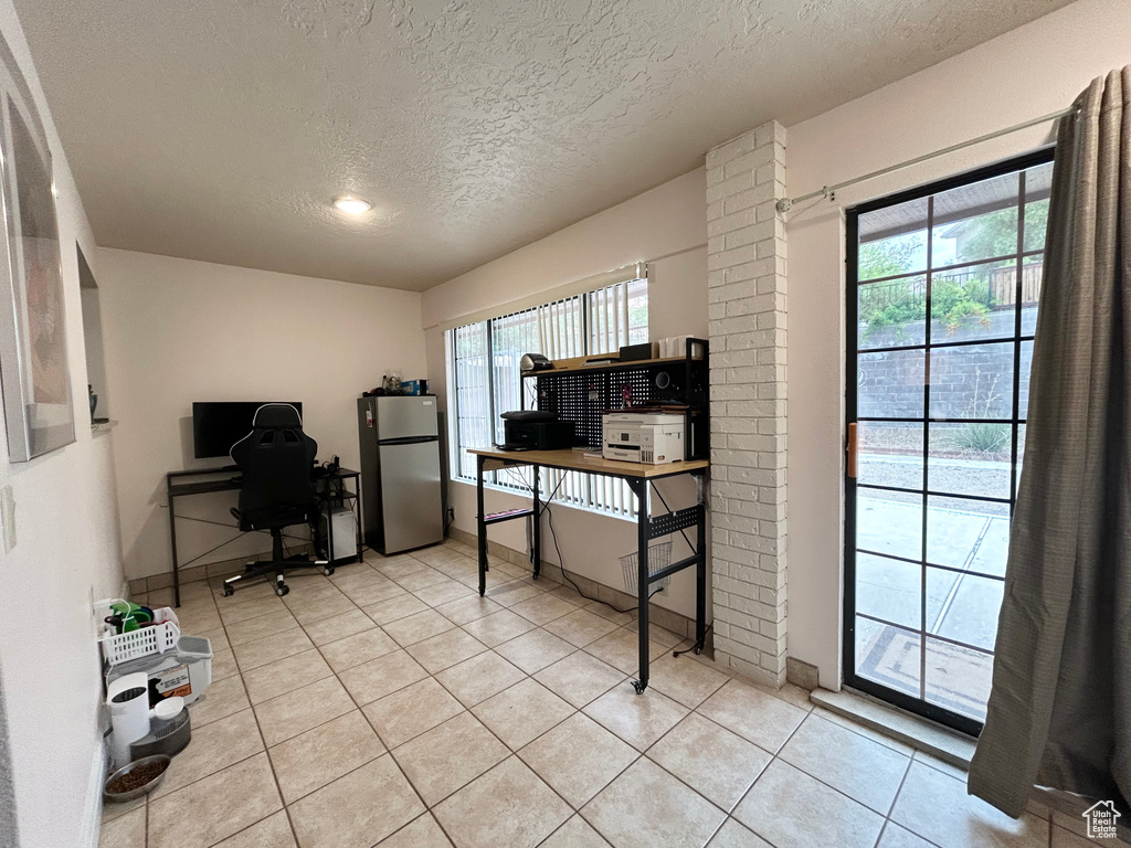 Home office featuring a textured ceiling, plenty of natural light, light tile patterned flooring, and baseboards