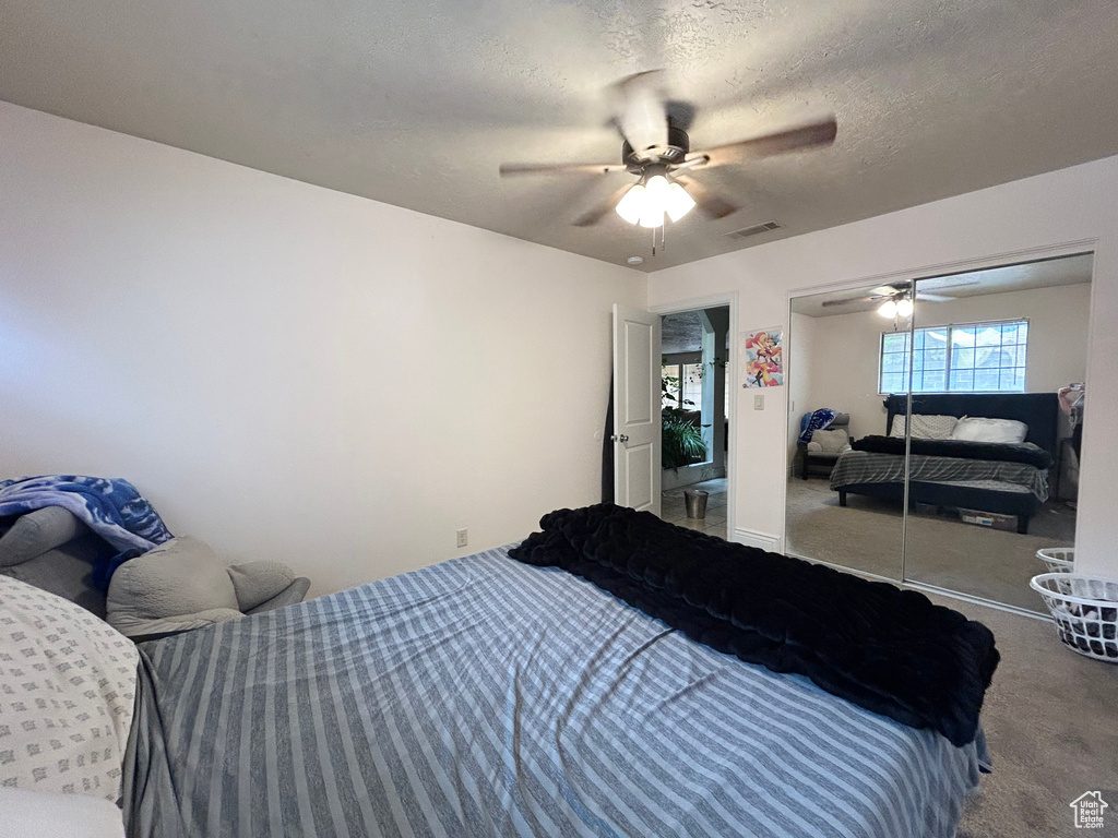 Bedroom featuring carpet floors, a ceiling fan, and a textured ceiling