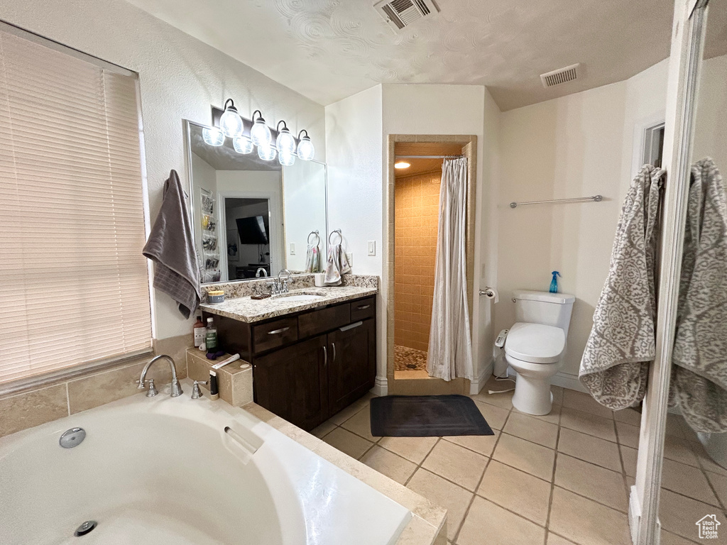 Full bathroom featuring toilet, vanity, a stall shower, a garden tub, and tile patterned floors