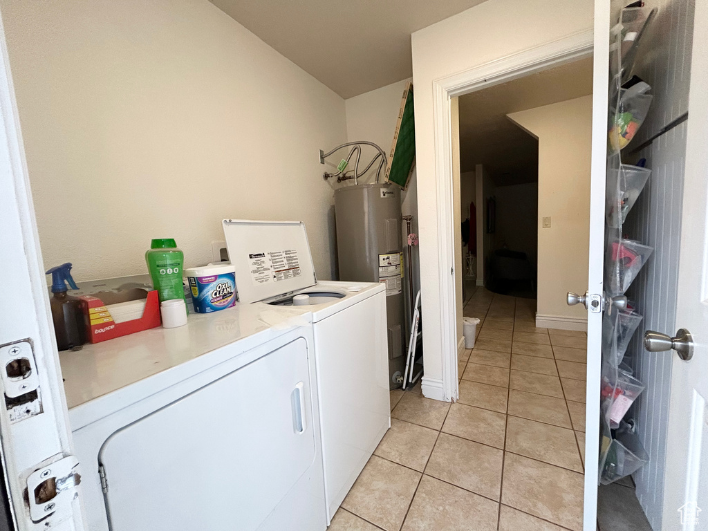 Laundry room with washer and dryer, light tile patterned floors, and electric water heater