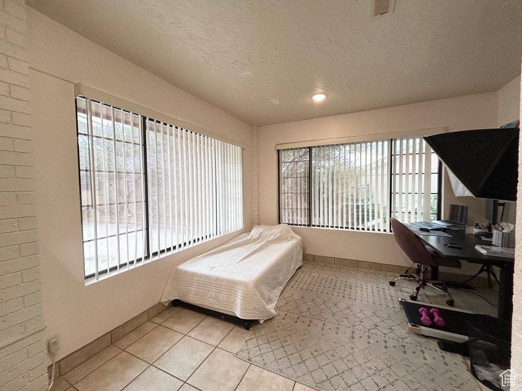 Bedroom featuring tile patterned floors, an office area, and a textured ceiling
