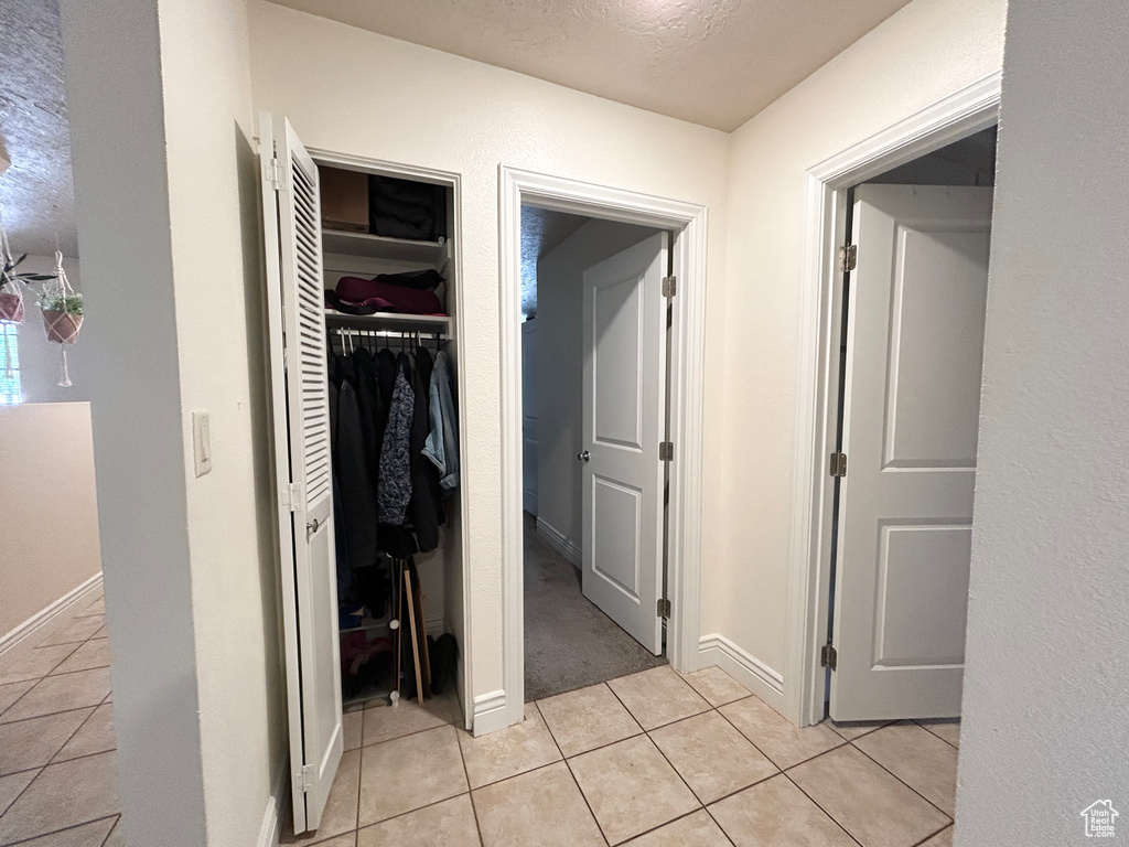 Hallway featuring light tile patterned floors and baseboards