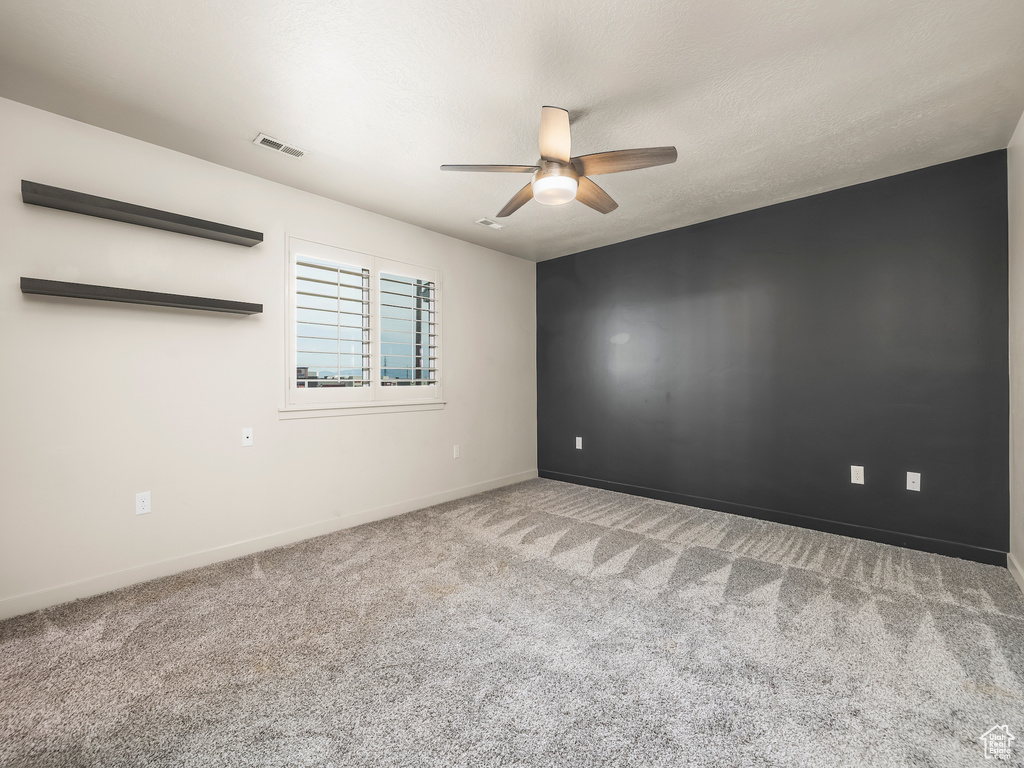 Carpeted spare room featuring ceiling fan and baseboards