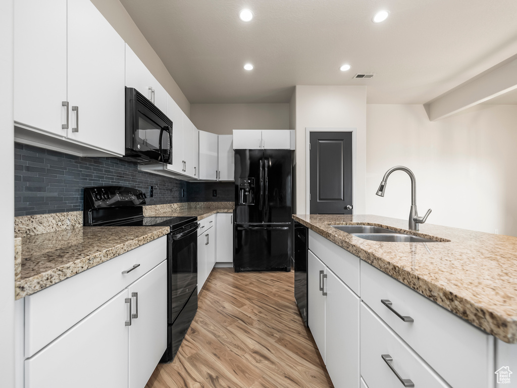 Kitchen featuring black appliances, a sink, light wood-style flooring, recessed lighting, and backsplash