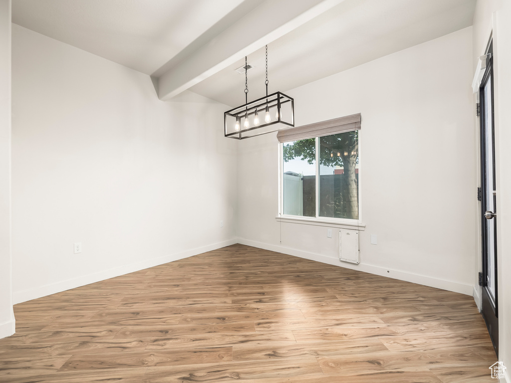 Unfurnished dining area with light wood-type flooring, baseboards, and a chandelier