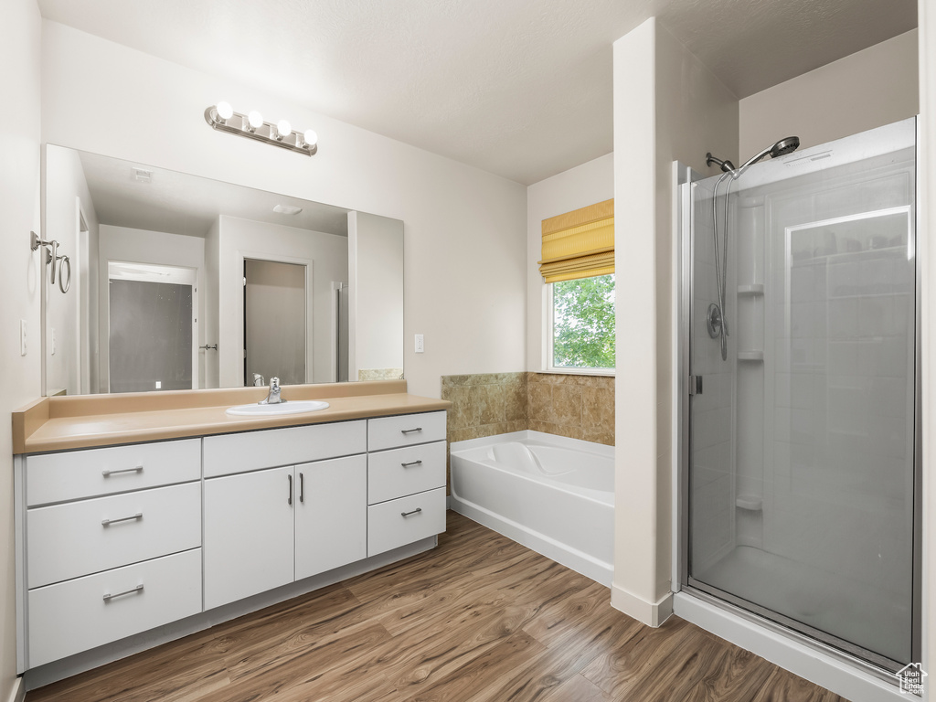 Full bathroom featuring vanity, a bath, wood finished floors, and a stall shower