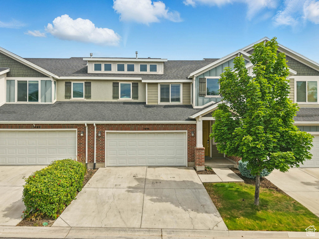 Townhome / multi-family property featuring an attached garage, concrete driveway, roof with shingles, and brick siding