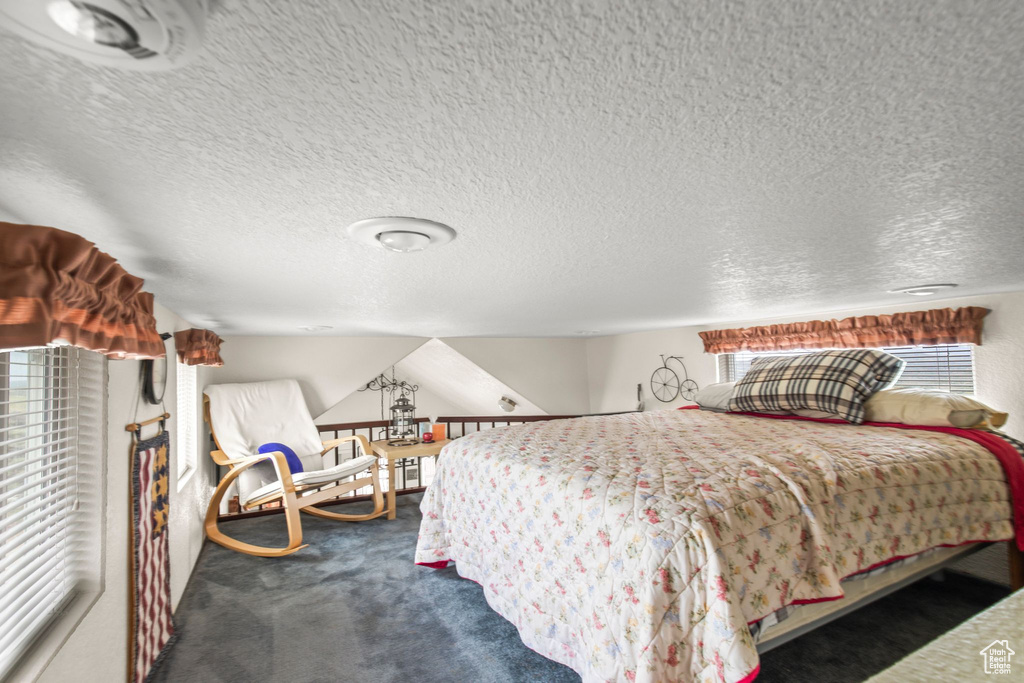 Bedroom featuring dark carpet and a textured ceiling