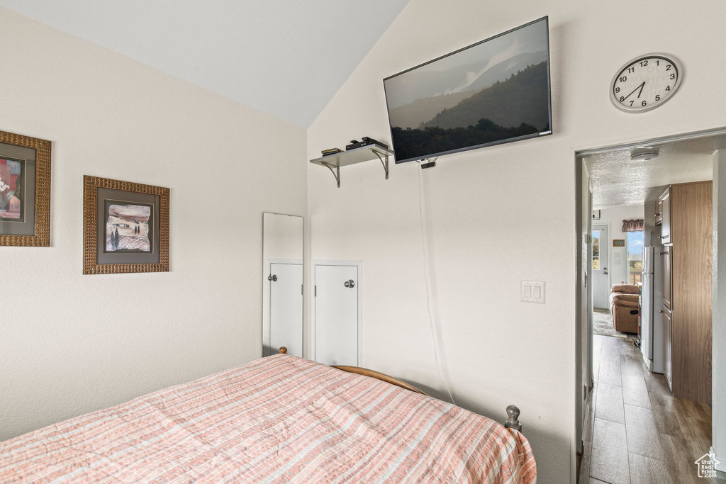 Bedroom featuring high vaulted ceiling and wood finished floors