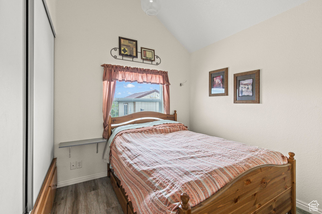 Bedroom featuring vaulted ceiling, wood finished floors, and baseboards