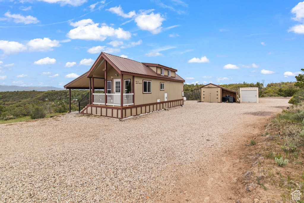 View of front of property featuring driveway, a porch, and metal roof