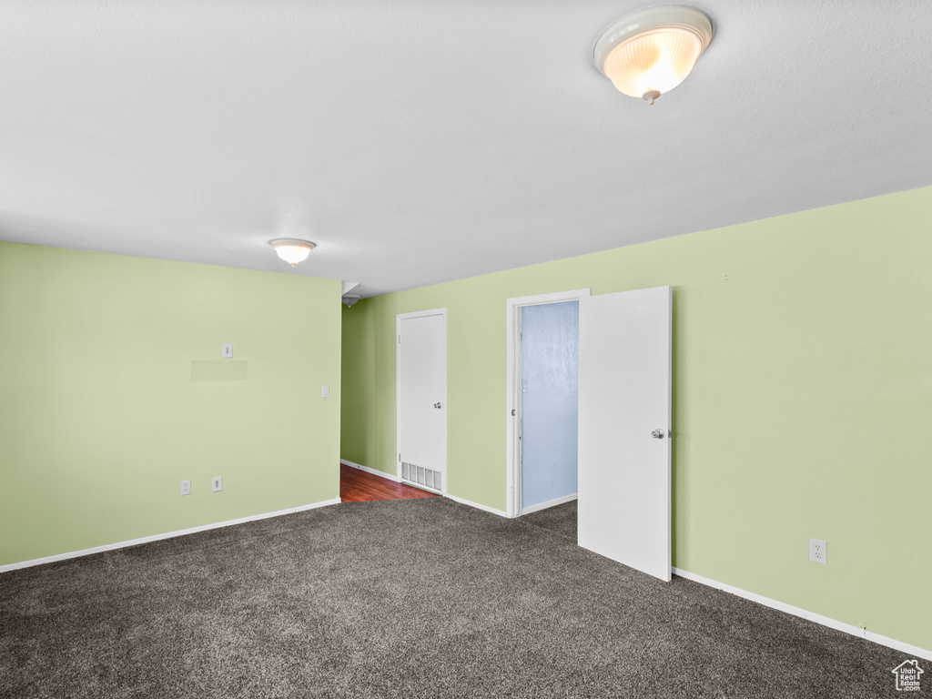 Spare room with dark carpet and baseboards