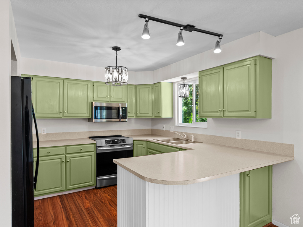 Kitchen with appliances with stainless steel finishes, a sink, a peninsula, and green cabinetry